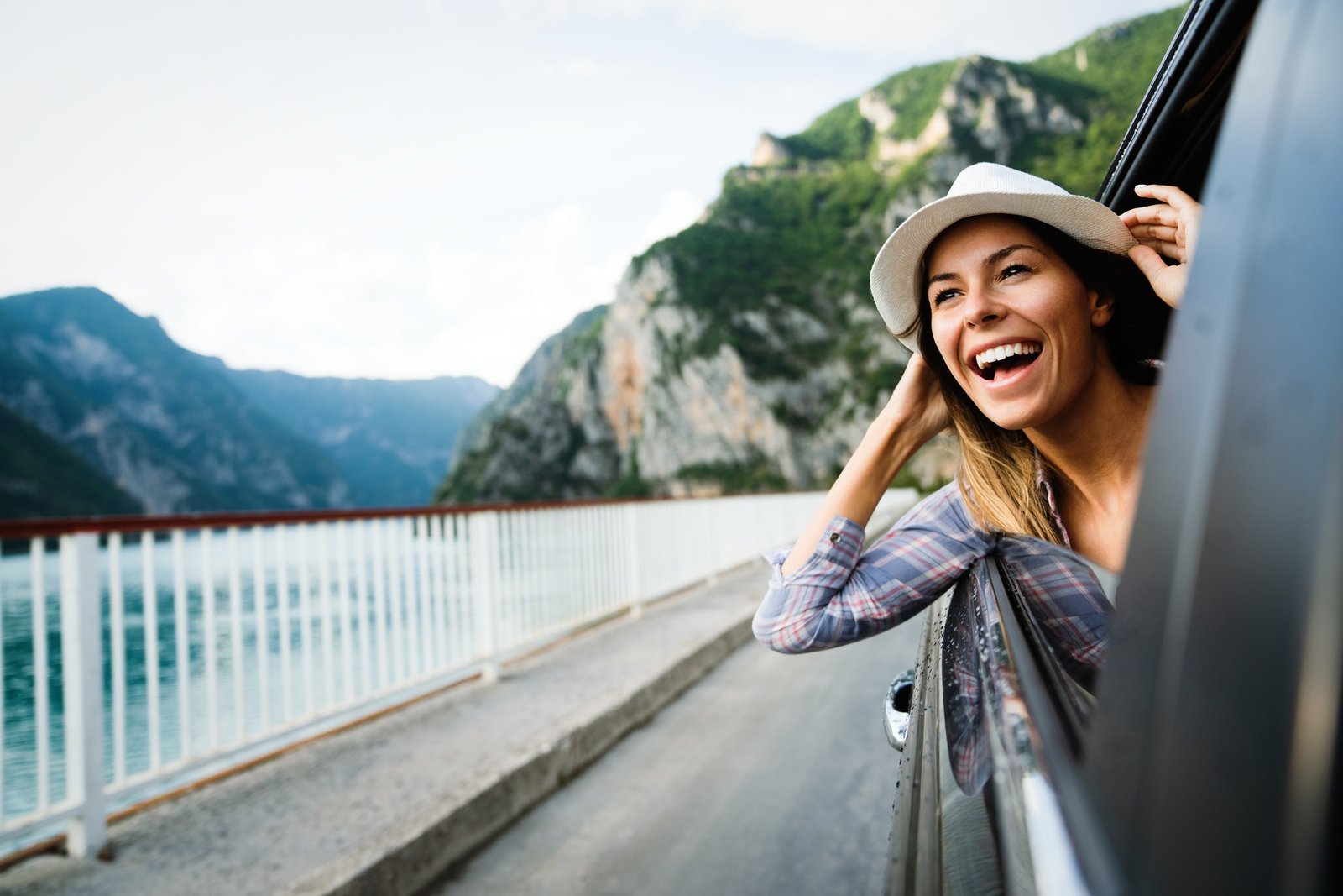Woman in car road trip waving out the window smiling